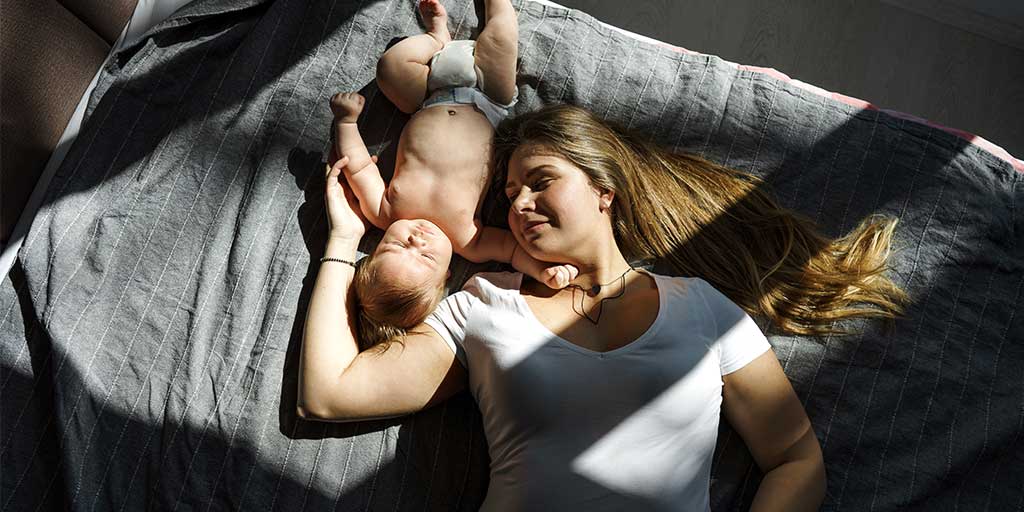 mother and baby lying on a bed