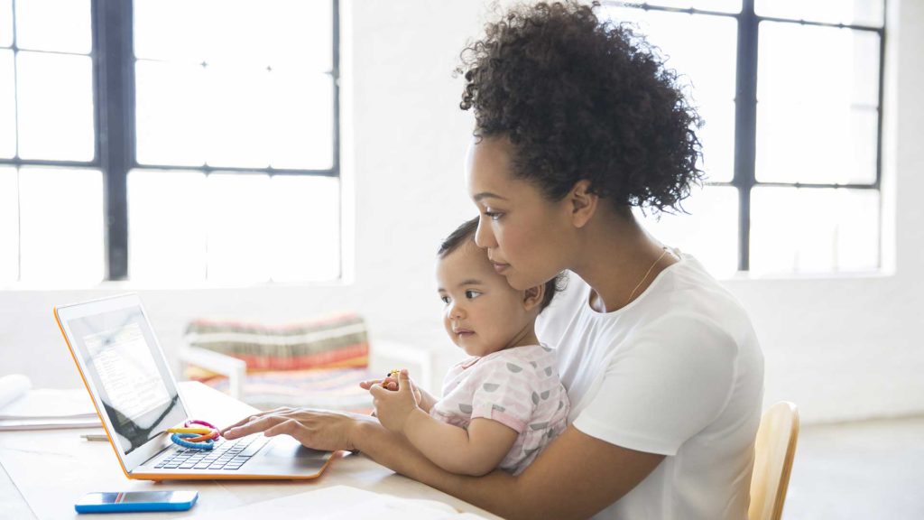 Mother working at laptop with baby